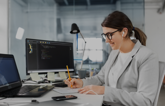 businesswoman in earphones with notebook and computers working at office