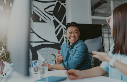 Handsome asian businessman working on laptop sitting in coworking on colleagues background