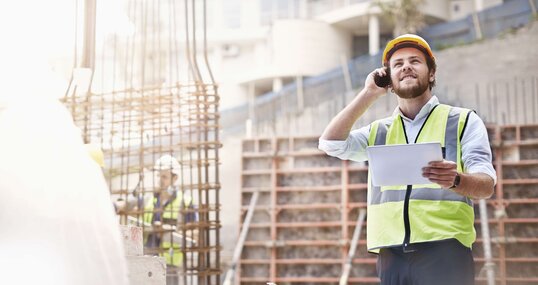 Ingenieur mit einem Tablet in der Hand telefoniert auf einer Baustelle