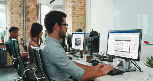 Focused at work. Side view of young busy employees working on computers while sitting at desk in modern open space